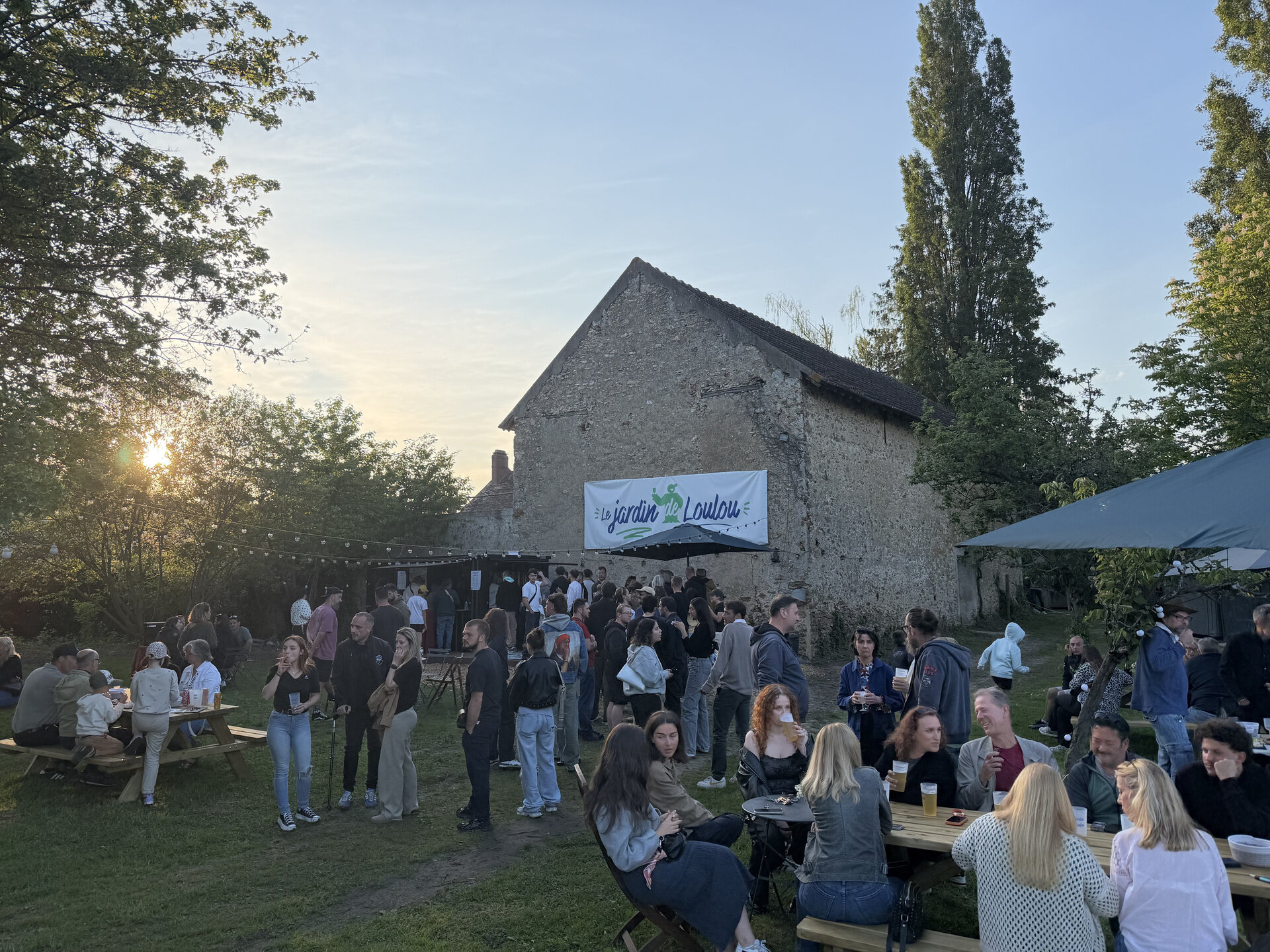 Foule au coucher de soleil au Jardin de Loulou — guinguette en plein air à Bullion